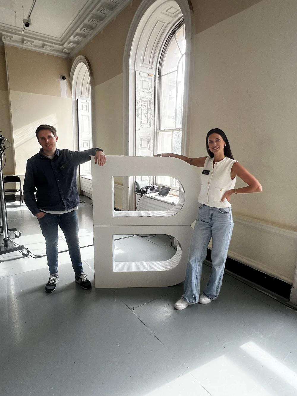 Two members of the Peak team beside a giant B Corp letter sculpture